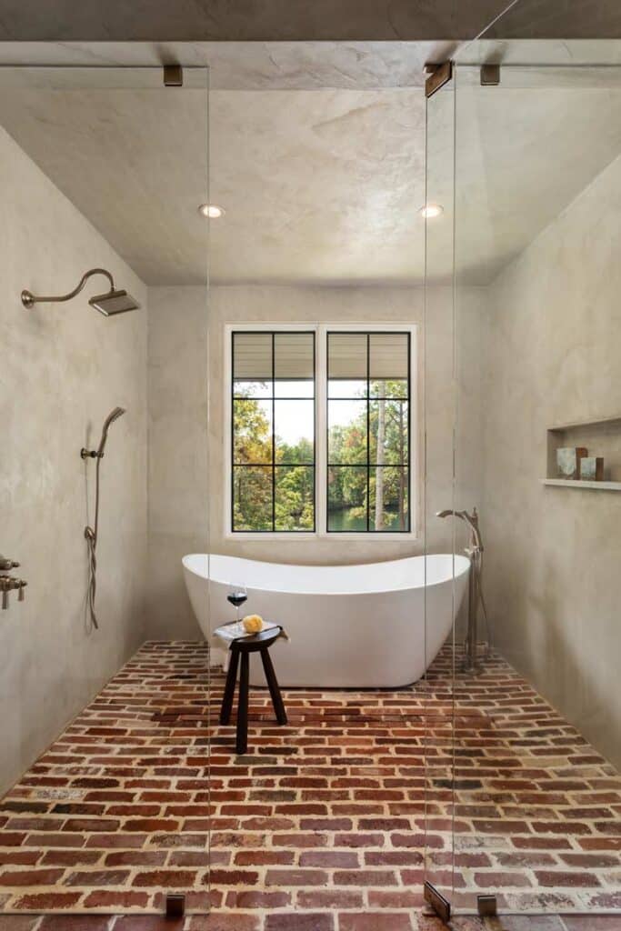 bathroom with soaking tub, glass walls and brick floor