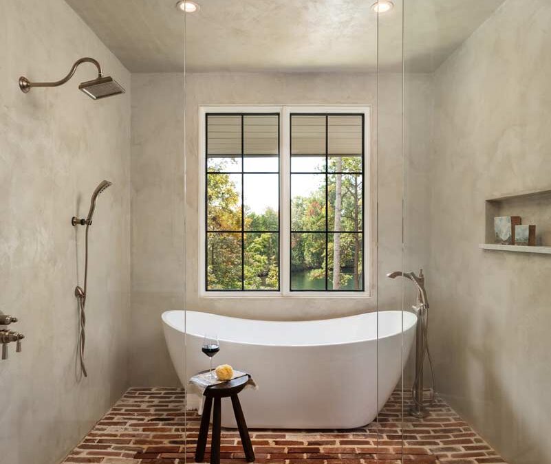 bathroom with soaking tub, glass walls and brick floor
